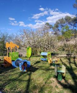 a group of childrens playground equipment in the grass at La cabane des Pachous in Tourves