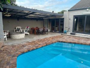 a backyard with a swimming pool and a patio with a table at Charming home, The Vines in Constantia in Cape Town