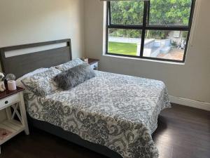 a bedroom with a bed with a blanket and a window at Charming home, The Vines in Constantia in Cape Town