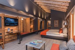 Un dormitorio con una cama, un televisor y un sofá. en BaseCamp Hotel, en Zermatt