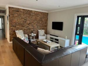 a living room with a couch and a brick wall at Charming home, The Vines in Constantia in Cape Town
