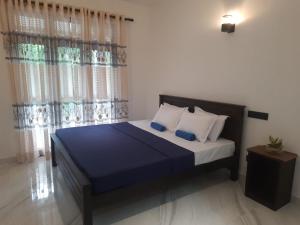 a bedroom with a bed with blue sheets and pillows at Villa Sunset Tides in Weligama