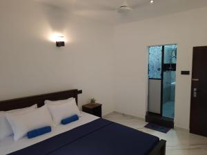 a bedroom with a bed with blue and white pillows at Villa Sunset Tides in Weligama