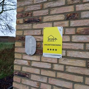 a sign on the side of a brick wall with a warning sign at De Molenlos in Zottegem