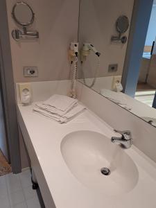 bagno con lavandino bianco e specchio di Hotel Internazionale a Cervignano del Friuli