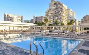 a large swimming pool with chairs and buildings at Ala Moana Hotel _ Ocean view with balcony in Honolulu