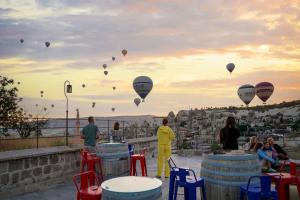 eine Gruppe von Menschen, die auf einem Felsvorsprung mit Heißluftballons stehen in der Unterkunft Tekkaya Cave Hotel in Goreme