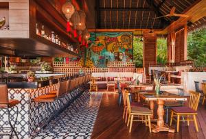 ヌエボ・バジャルタにあるBON Park Hotel at VidantaWorld Nuevo Vallartaの木製のテーブルと椅子、壁画のあるレストラン