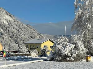 a yellow house in the mountains with snow on it at Haus Grimm - Apartment Katharina in Scheifling