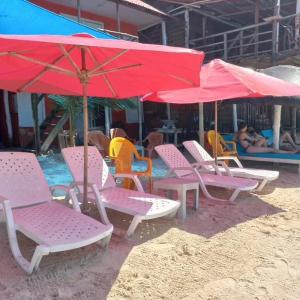 Playa Tortuga Cabaña في بلايا بلانكا: مجموعة من الكراسي والمظلات على الشاطئ