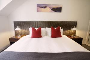 a bedroom with a white bed with red pillows at Lantern 1 Bedroom Balcony with Panoramic Alpine View in Thredbo