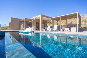 a swimming pool with chairs and a house at Olive and Aloe Villas in Nomikianá