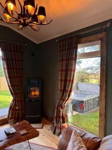 sala de estar con chimenea y ventana grande en Hunters Glebe Lodge, en Castlerock