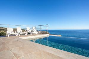 une piscine avec des chaises et l'océan en arrière-plan dans l'établissement Olive and Aloe Villas, à Nomikianá