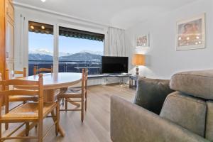 a living room with a table and a couch at Logement avec vue époustouflante sur les montagnes in Crans-Montana