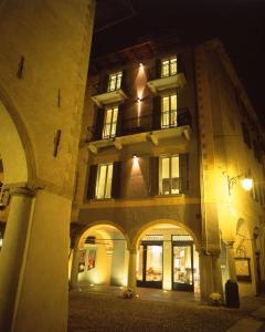 un grande edificio con archi di fronte ad esso di notte di Hotel Aracoeli a Orta San Giulio