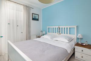 a bedroom with a white bed and blue walls at Maritime Cosy Apartment in Świnoujście