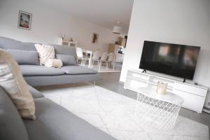 ein Wohnzimmer mit einem Sofa und einem Flachbild-TV in der Unterkunft Beautiful 4BR House with Jacuzzi in Sandweiler