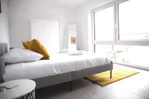 een slaapkamer met een bed met witte lakens en gele kussens bij Beautiful 4BR House with Jacuzzi in Sandweiler