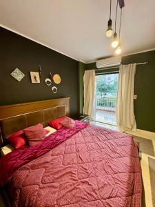 een slaapkamer met een bed met een rood dekbed en een raam bij Vintage/Modern 3BR Apt+Huge Discount@Madinaty in Madinaty