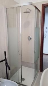 La salle de bains est pourvue d'une douche avec une porte en verre. dans l'établissement casa bilocale in centro vicino stazione, à Voghera