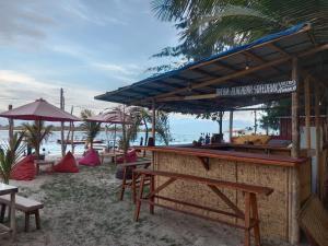 eine Bar am Strand mit Tischen und Sonnenschirmen in der Unterkunft fullesguesthouse in Gili Trawangan