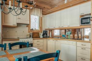 una cocina con armarios blancos y una mesa con sillas. en Villa Ojala, a lovely cottage with own beach, en Kuusamo
