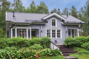 una pequeña casa gris con porche y algunos arbustos en Villa Ojala, a lovely cottage with own beach, en Kuusamo