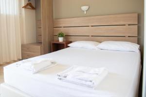 a bedroom with a white bed with two towels on it at Tota Marinou in Agioi Apostoli