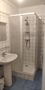 La salle de bains blanche est pourvue d'une douche et d'un lavabo. dans l'établissement Appartements simples et fonctionnels, à Pamiers