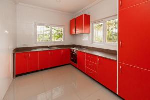 eine rote Küche mit weißen Wänden und roten Schränken in der Unterkunft BRAGHA APARTMENTS in Takoradi