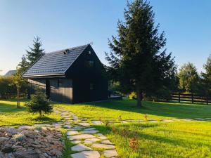 a black barn with a stone path in front of it at laba in Lasowka