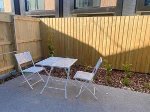 Una mesa y dos sillas al lado de una valla en addington luxury townhouse, en Christchurch