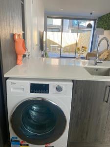 una lavadora en una cocina con fregadero en addington luxury townhouse, en Christchurch 7 fotos más