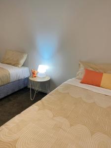 una habitación con dos camas y una mesa con lámpara en addington luxury townhouse, en Christchurch