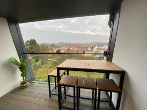 einen Balkon mit einem Tisch, 2 Bänken und einem großen Fenster in der Unterkunft Luxury & cozy apartment in Lubbeek