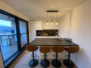a kitchen with a island with three bar chairs at Luxury & cozy apartment in Lubbeek
