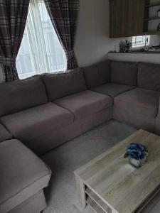 ein Wohnzimmer mit einem braunen Sofa und einem Couchtisch in der Unterkunft hot tub luxury caravan 23 Lancaster tattershall lakes in Tattershall