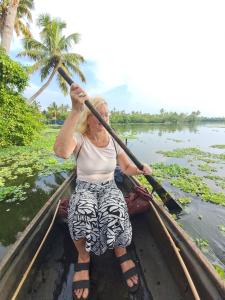 a woman is rowing a boat on the water at Marari Bethsaida Homestay in Shertallai