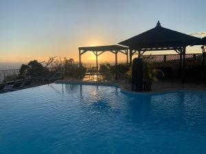 uma grande piscina com um pôr-do-sol ao fundo em Residence Les Lataniers em Saint-Leu
