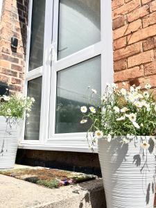 two white vases with flowers in them in front of a window at Modern boutique apartment for 4- central Ellesmere in Ellesmere