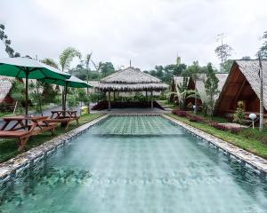 a swimming pool with two tables and a pavilion at New Dgyp Ciater Resort in Ciater