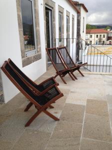 two wooden chairs sitting on a balcony at Casa das Boticas in Paredes de Coura