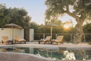 a group of chairs and umbrellas next to a pool at Nono's Fioro Premium Houses, By TK Property Management in Gaïtánion +52 photos