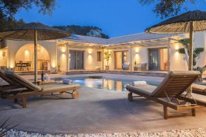 a house with a pool and two chairs and an umbrella at Nono's Fioro Premium Houses, By TK Property Management in Gaïtánion