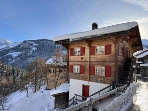 a wooden house with red doors in the snow at Bambi Lodge Ferienwohnung auf knapp 1400 m nahe Arosa in Peist