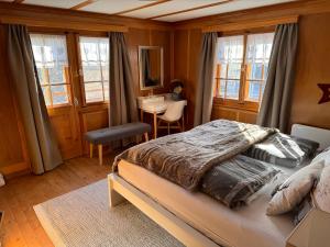 a bedroom with a bed and a desk and windows at Bambi Lodge Ferienwohnung auf knapp 1400 m nahe Arosa in Peist