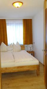 ヴェステンドルフにあるAppartment-Haus Janineのベッドルーム1室(白いシーツ付きのベッド1台、窓付)