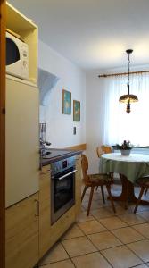 eine Küche und ein Esszimmer mit einem Tisch und einer Mikrowelle in der Unterkunft Appartment-Haus Janine in Westendorf
