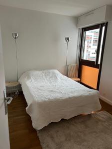 a bedroom with a white bed and a window at Appartement lumineux 2 pièces Paris – idéal famille in Paris
